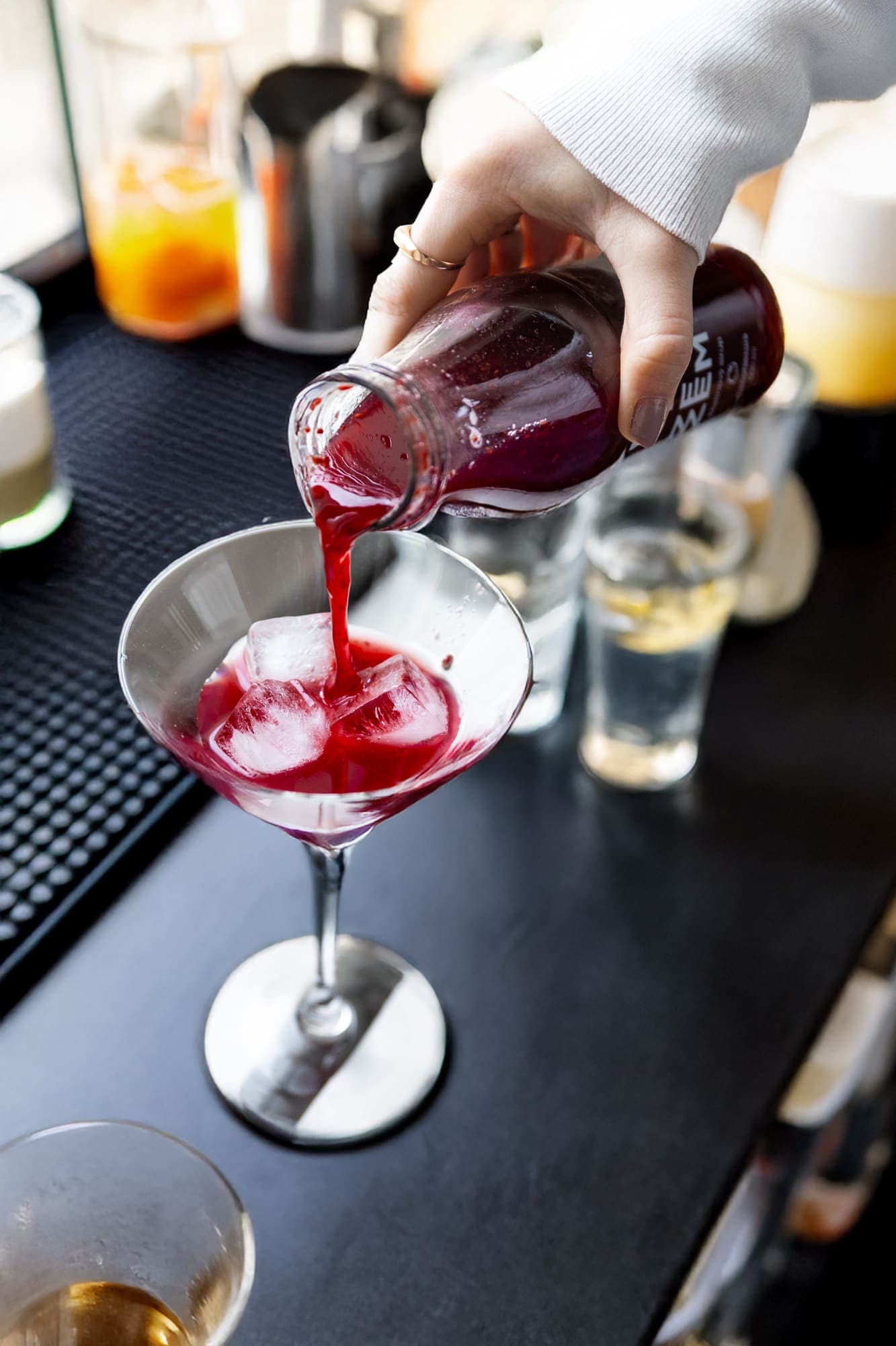 Barman přelévá sirup ZEZEM do sklenice s koktejlem